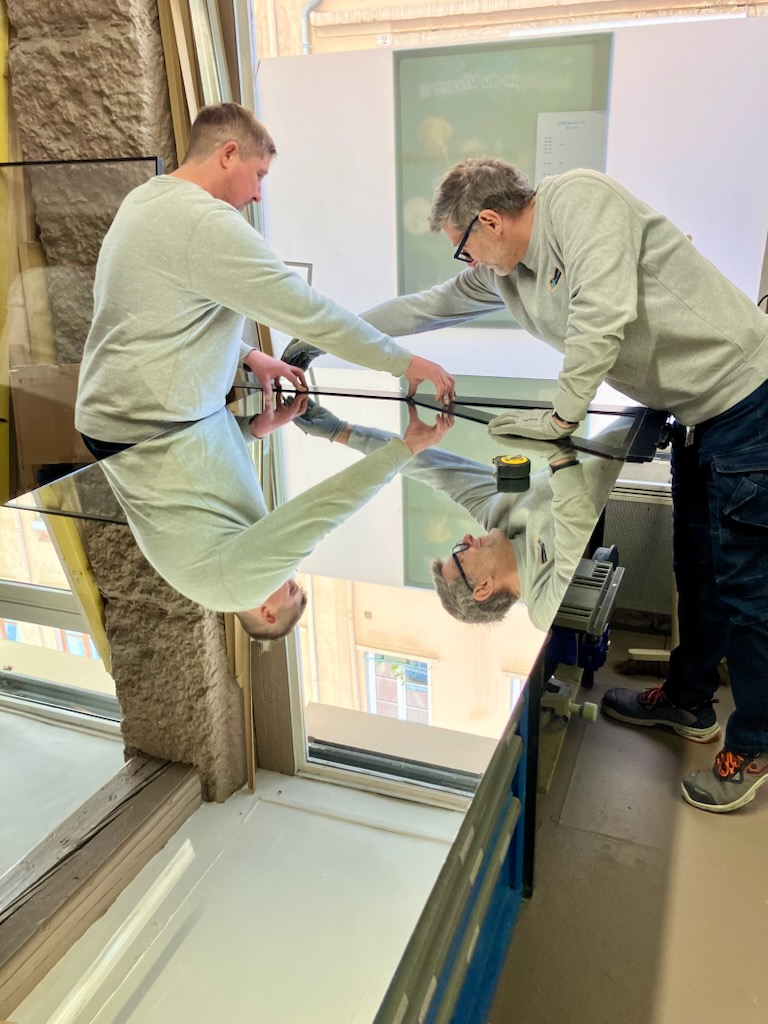 Artisans vitriers mesurant et découpant un miroir dans notre atelier